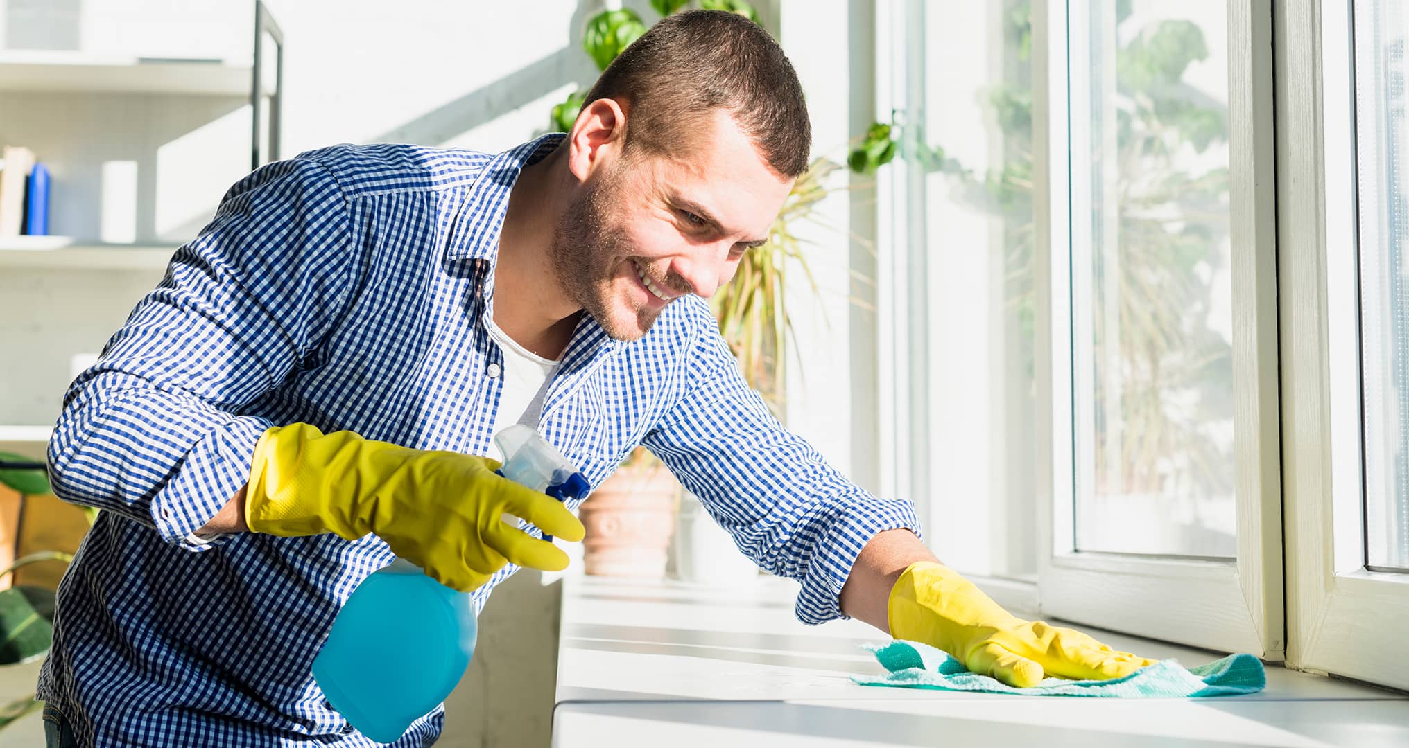 man deep cleaning office with spray bottle and cleaning gloves